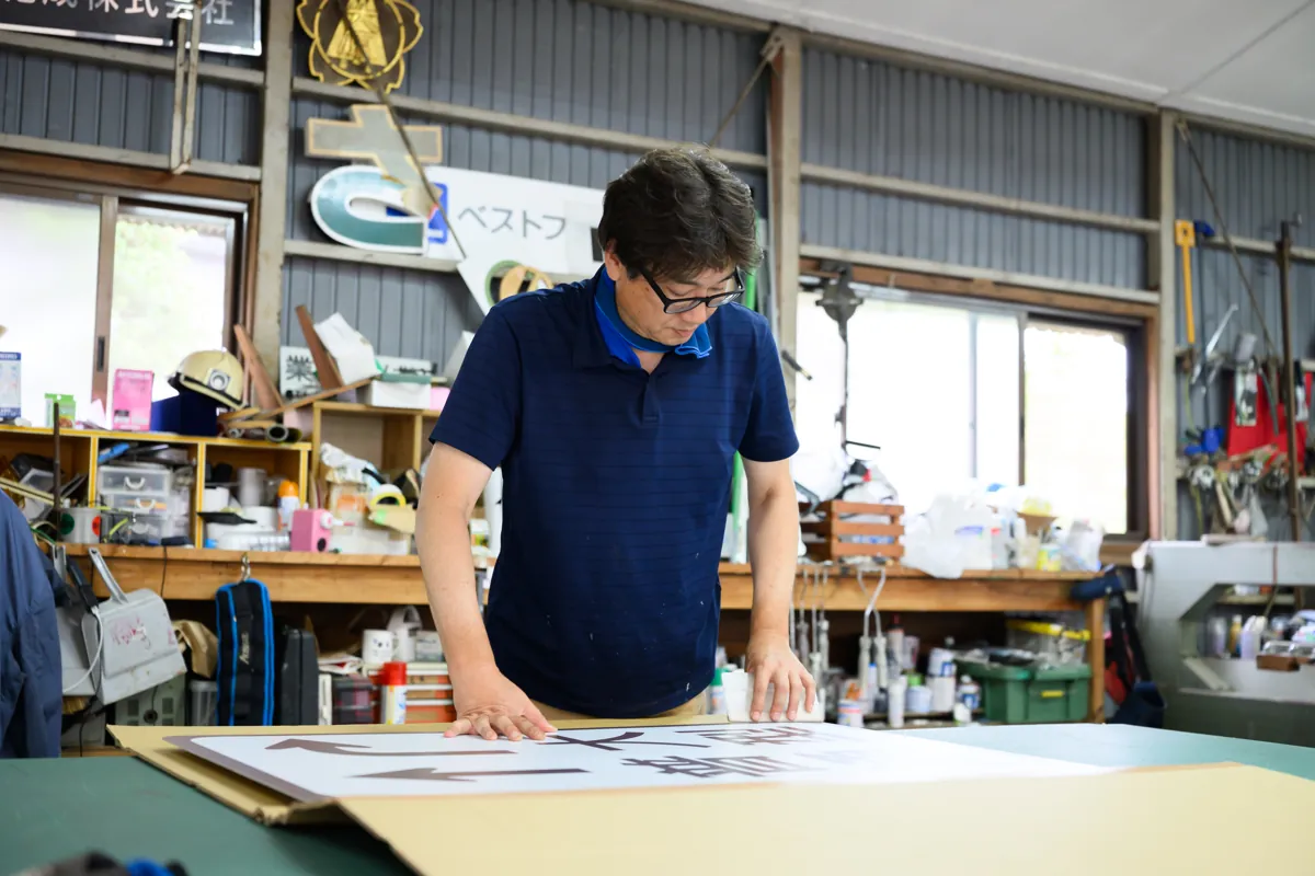 工房で看板パネルを制作する有限会社マルニ工芸の職人